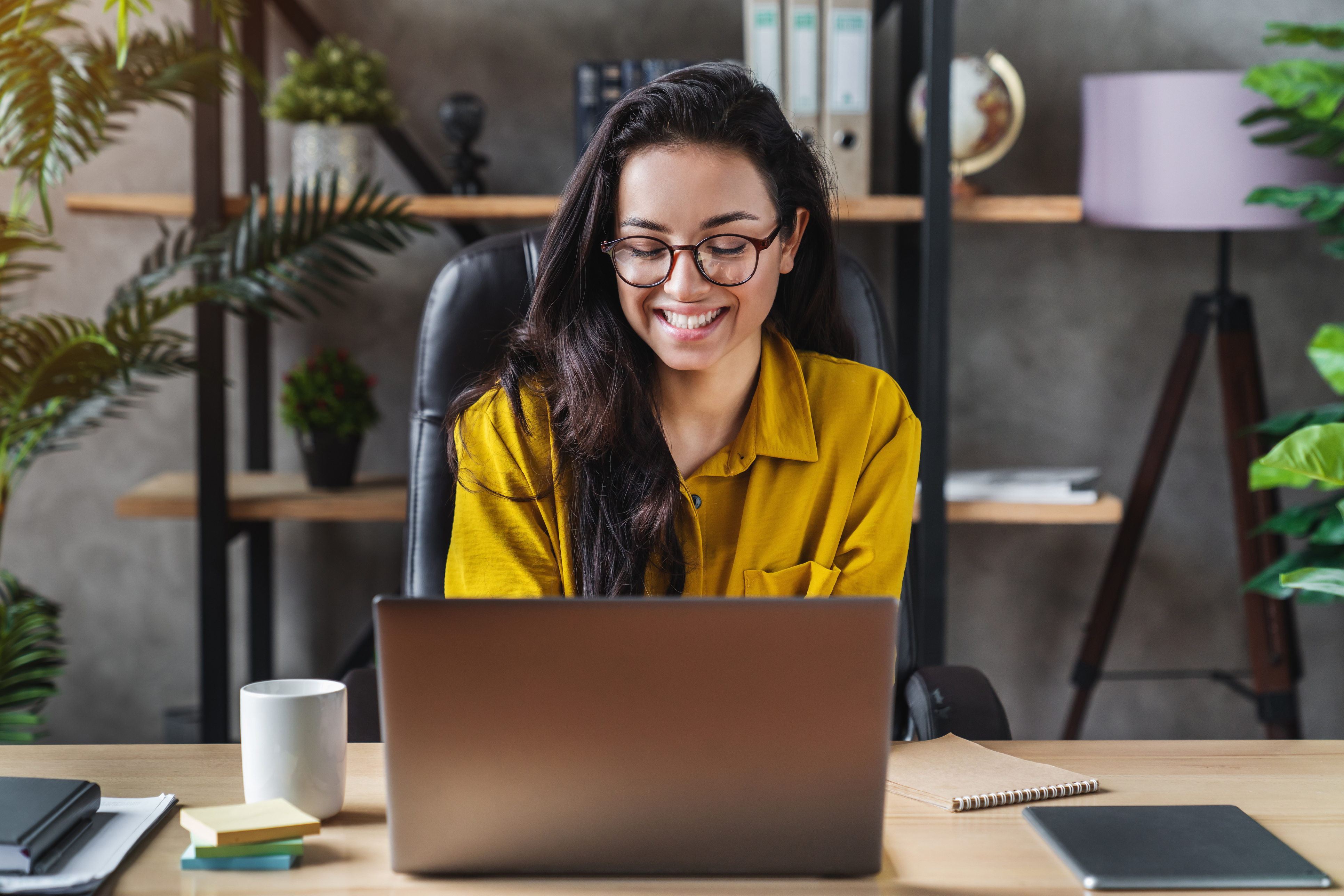 Smiling woman on laptop in office.